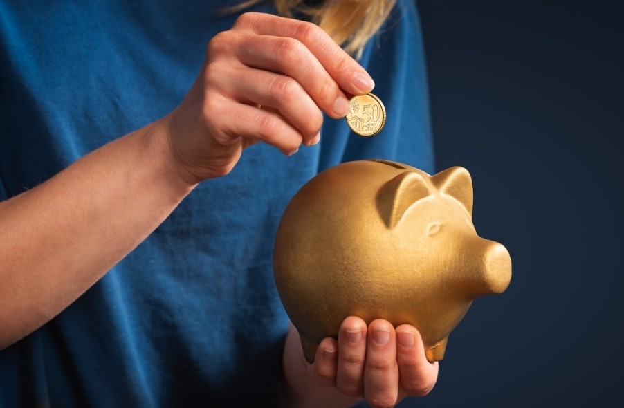 placing gold coins in a piggy bank as a symbol of gold investing