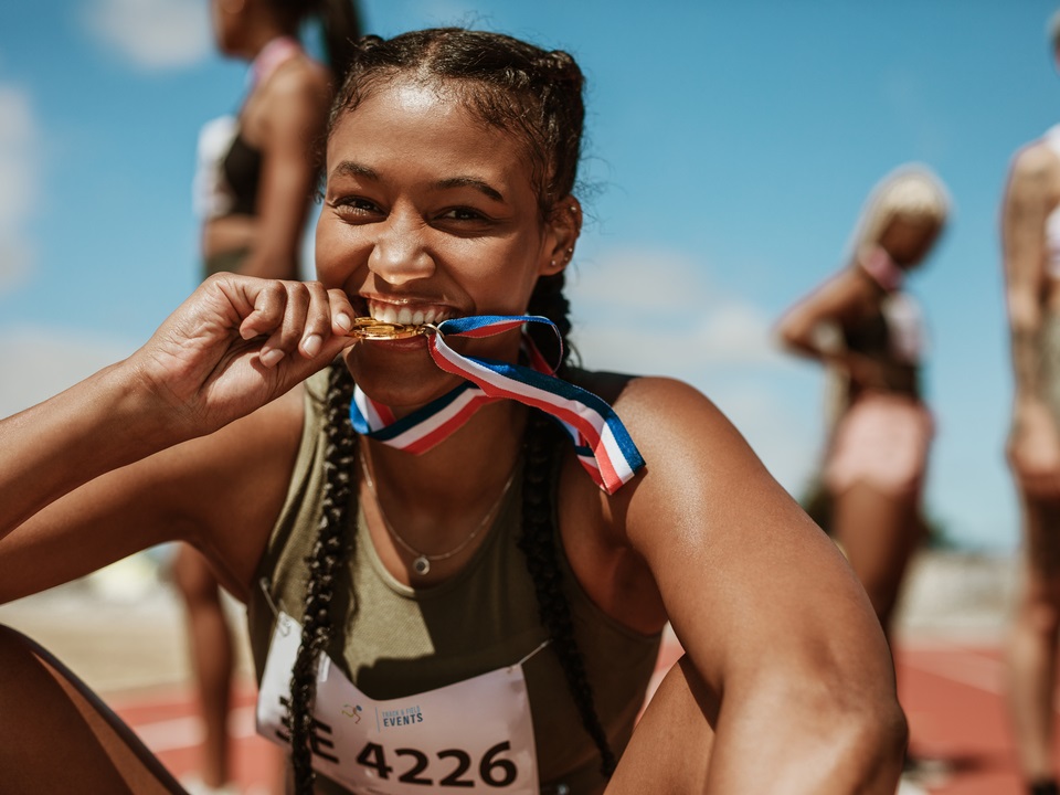excited athlete biting her gold medal