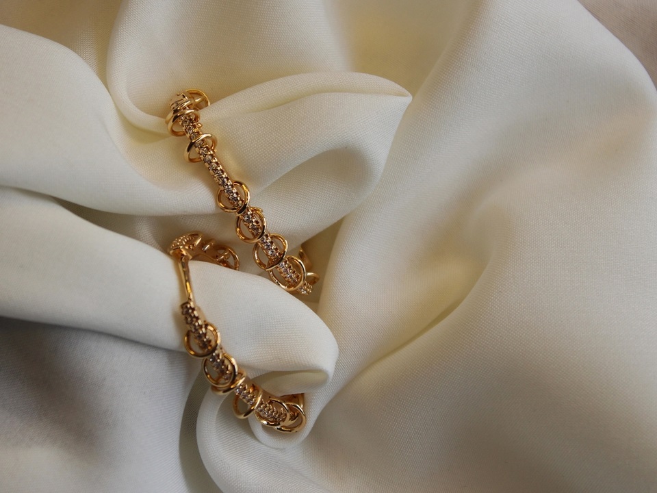 gold earrings at top of white satin