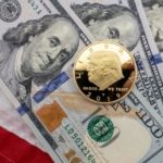 trump gold coin on top of us dollar bills