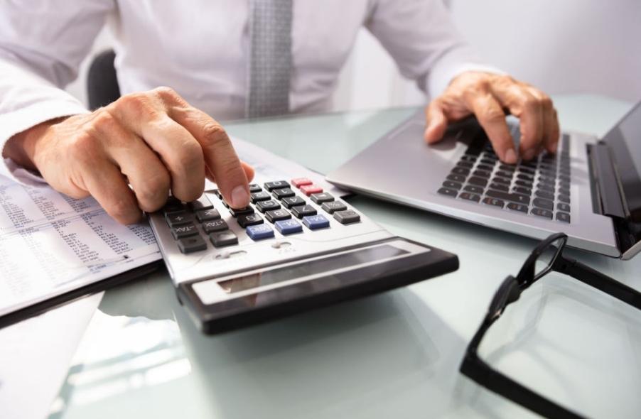 businessmans hand using calculator and laptop managing his annual payment