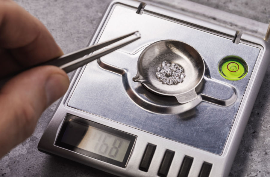 specialist measures weight of gems on a jewelry scale