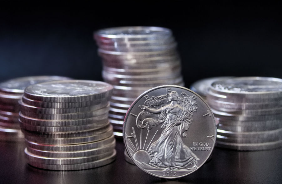 one ounce american eagle silver coin in front of stacks silver coins