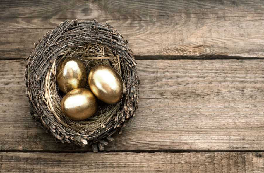 gold eggs in birds nest over wooden background