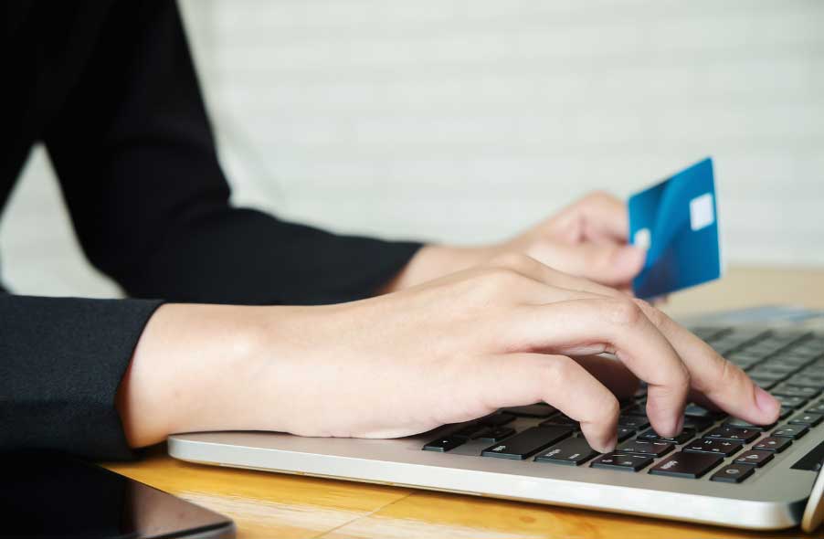 woman holding credit card and using laptop