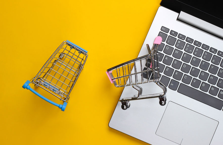 two shopping cart and laptop on gold background