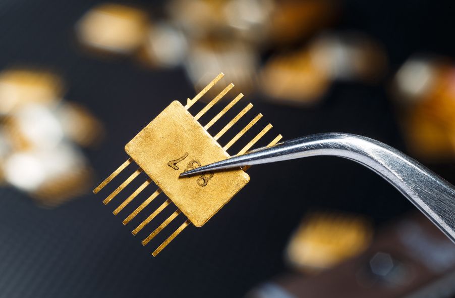golden microchip with tweezers on electric components background